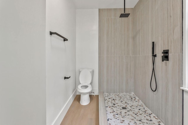 full bathroom featuring a tile shower, wood finished floors, toilet, and baseboards
