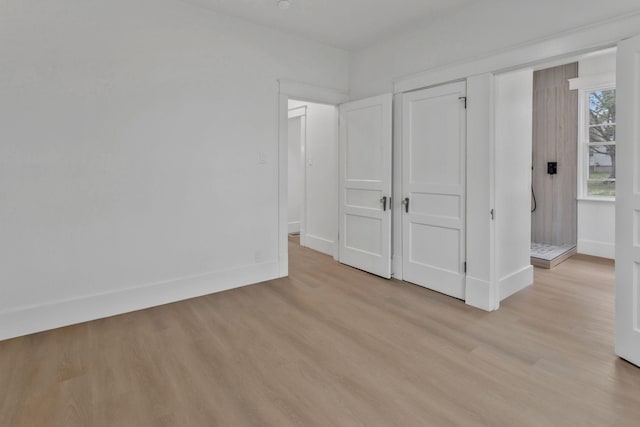 unfurnished bedroom with light wood-type flooring, baseboards, and a closet