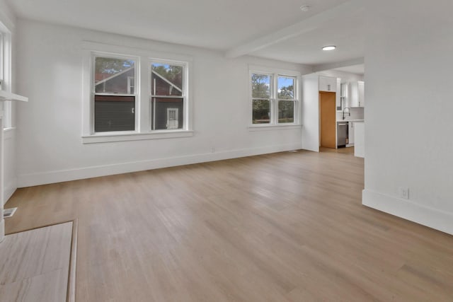unfurnished living room featuring light wood-type flooring, baseboards, and a sink
