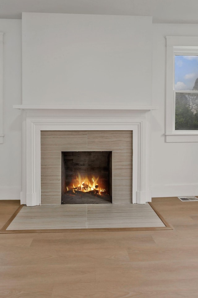 detailed view of a warm lit fireplace, baseboards, and wood finished floors