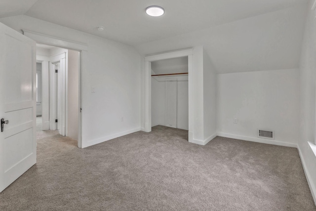 unfurnished bedroom with carpet, vaulted ceiling, a closet, and baseboards