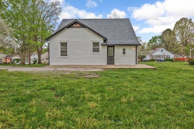 back of house featuring a shingled roof and a yard