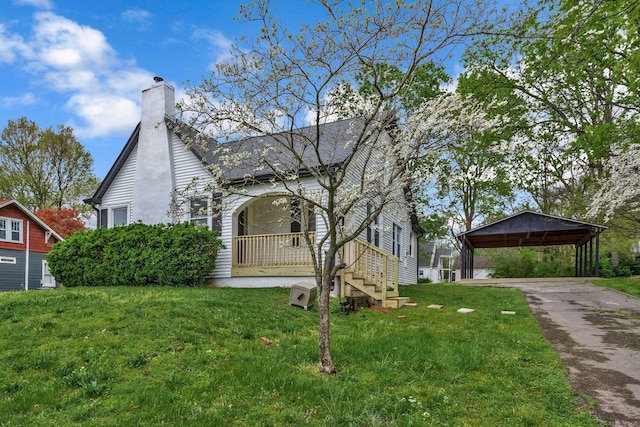 view of front of home featuring a carport, a front lawn, driveway, and a chimney