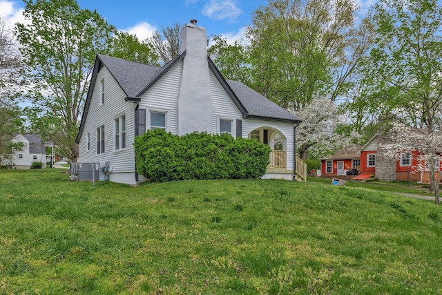 view of front of property with a chimney, a front lawn, and a shingled roof