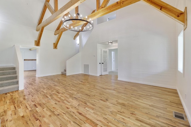 unfurnished living room featuring stairway, high vaulted ceiling, wood finished floors, beamed ceiling, and a chandelier