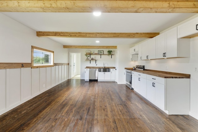 kitchen with appliances with stainless steel finishes, butcher block counters, dark wood-style floors, beamed ceiling, and white cabinetry