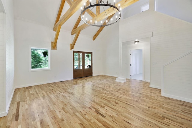 unfurnished living room featuring high vaulted ceiling, light wood-style flooring, beam ceiling, a chandelier, and baseboards