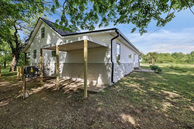 view of side of property featuring a lawn and a carport