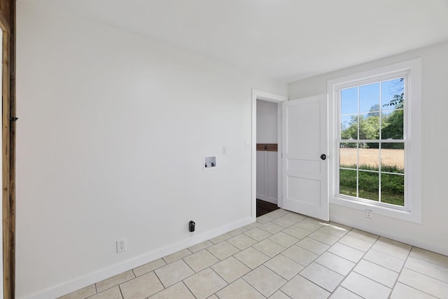 spare room featuring light tile patterned floors and baseboards