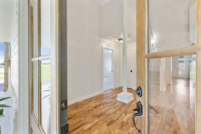 interior space featuring light wood-type flooring, baseboards, and a high ceiling