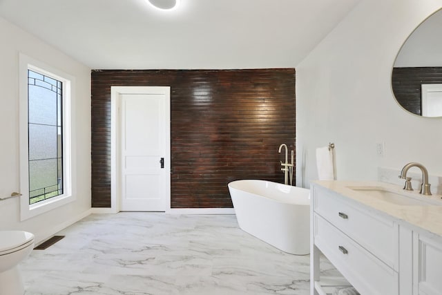 full bath with marble finish floors, plenty of natural light, an accent wall, and a freestanding bath