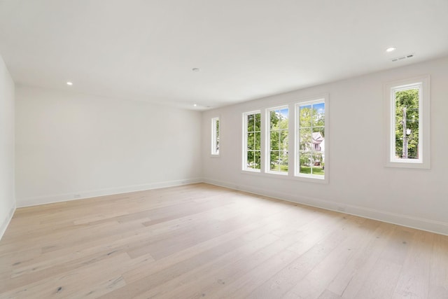 empty room with healthy amount of natural light, baseboards, light wood-type flooring, and recessed lighting