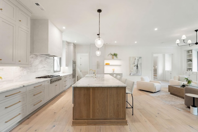 kitchen featuring appliances with stainless steel finishes, a sink, custom exhaust hood, light wood-type flooring, and open floor plan