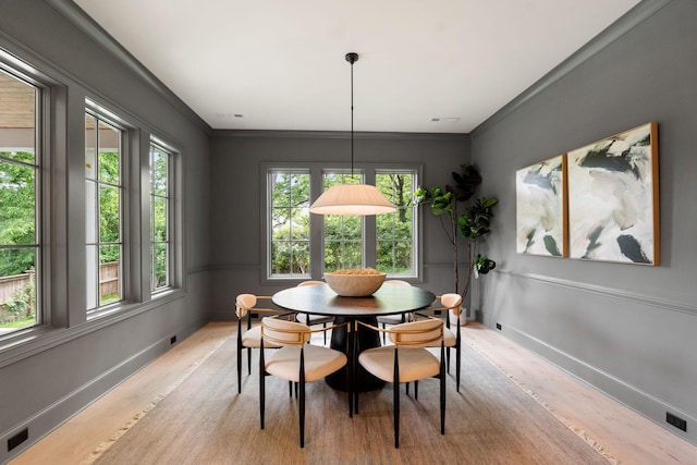 dining area with plenty of natural light, light wood finished floors, ornamental molding, and baseboards