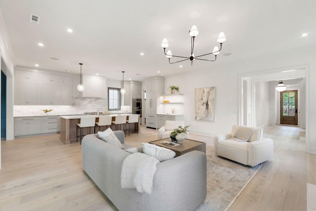 living area with a chandelier, light wood-style flooring, and recessed lighting