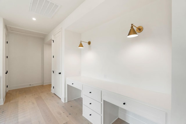 unfurnished office featuring light wood-style flooring, recessed lighting, built in desk, and baseboards