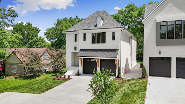view of front facade with a garage, a standing seam roof, driveway, a front yard, and brick siding