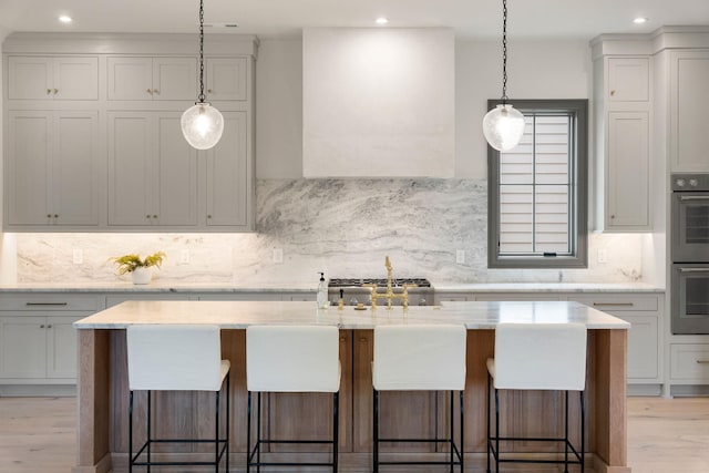 kitchen with double oven, light wood-type flooring, decorative backsplash, a breakfast bar, and recessed lighting