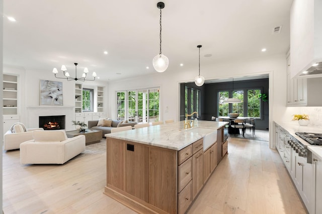 kitchen featuring a sink, stainless steel gas cooktop, light wood-type flooring, recessed lighting, and a spacious island