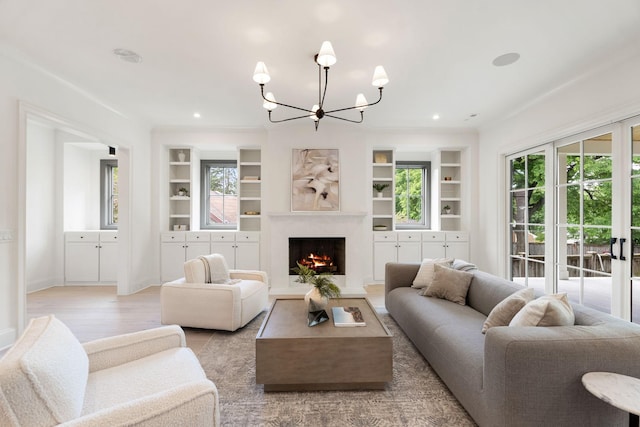 living area with a chandelier, built in shelves, a high end fireplace, light wood-type flooring, and recessed lighting