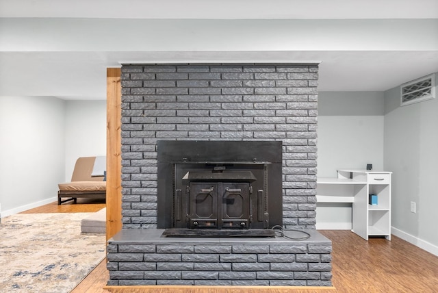 detailed view of a brick fireplace, wood finished floors, and baseboards