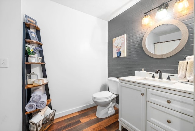 bathroom with wood finished floors, vanity, toilet, and baseboards