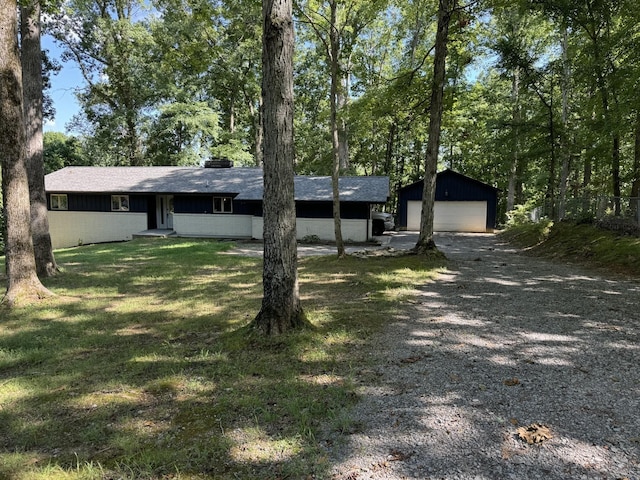 view of front facade featuring a detached garage, driveway, an outdoor structure, and a shingled roof