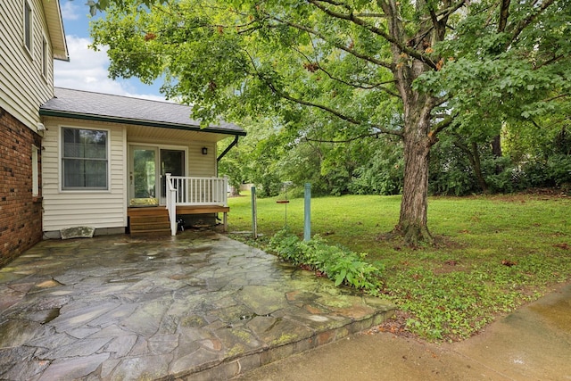 view of grassy yard featuring a patio area and a wooden deck