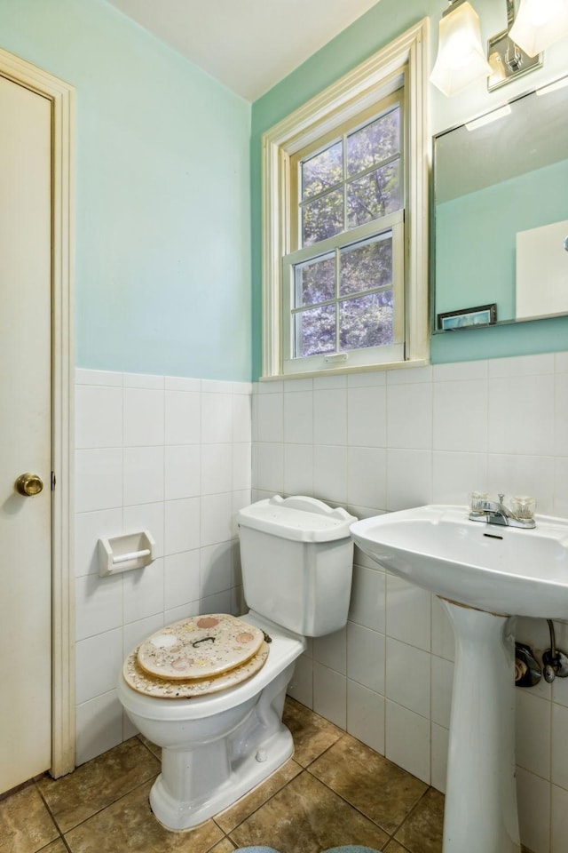 bathroom with tile walls, toilet, tile patterned floors, and a sink