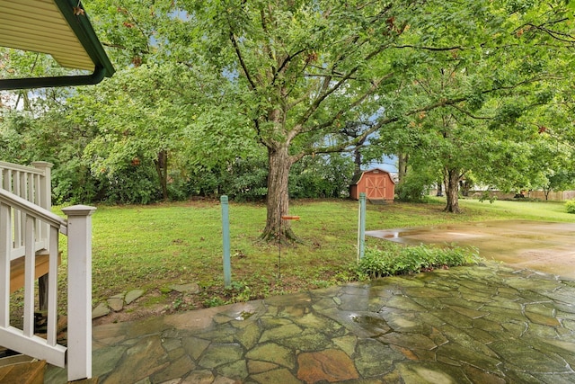 view of green lawn featuring a shed, a patio, and an outbuilding