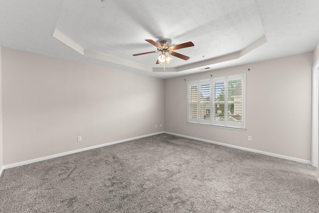 carpeted empty room with a tray ceiling, ceiling fan, a textured ceiling, and baseboards