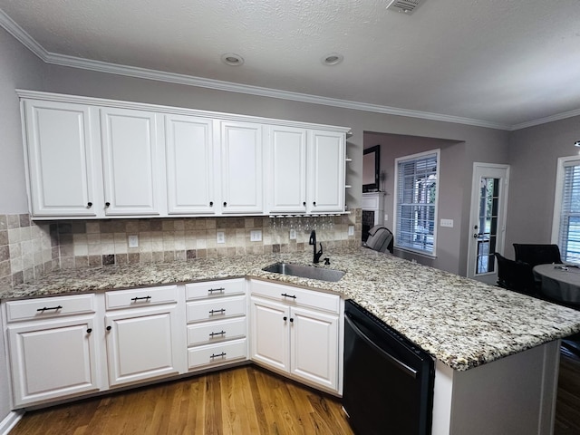 kitchen featuring black dishwasher, a sink, a peninsula, wood finished floors, and white cabinets