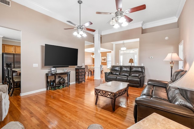 living area with a ceiling fan, crown molding, light wood-style flooring, baseboards, and ornate columns