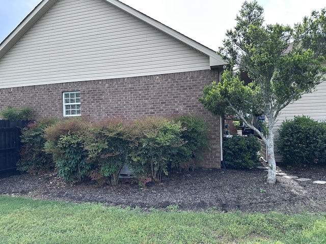 view of home's exterior featuring brick siding and fence