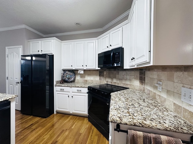 kitchen featuring black appliances, light wood finished floors, white cabinets, crown molding, and decorative backsplash