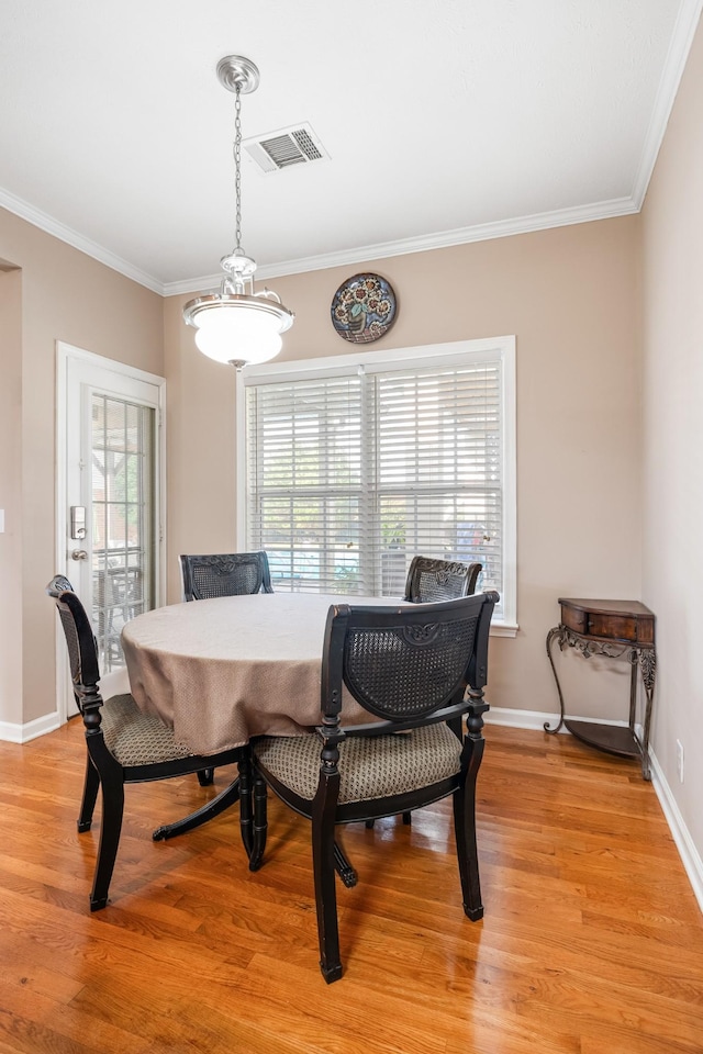 dining area with light wood-type flooring, crown molding, and baseboards