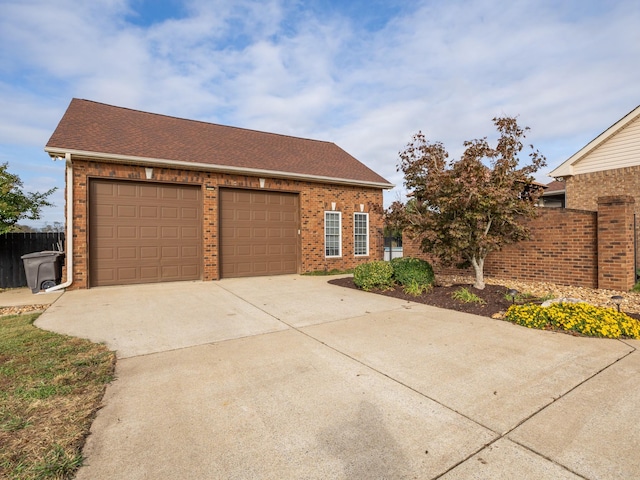 view of front of house featuring driveway, brick siding, fence, a garage, and roof with shingles