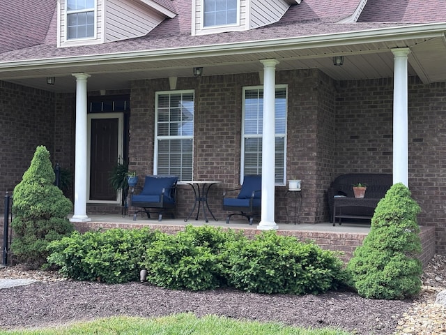 entrance to property featuring a porch and brick siding