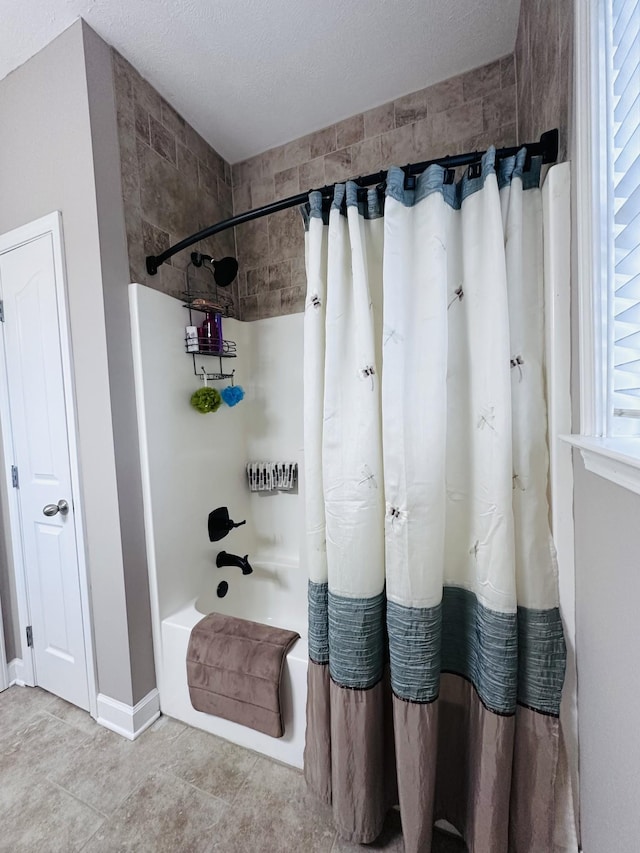 full bath with shower / bath combo, baseboards, a textured ceiling, and tile patterned flooring