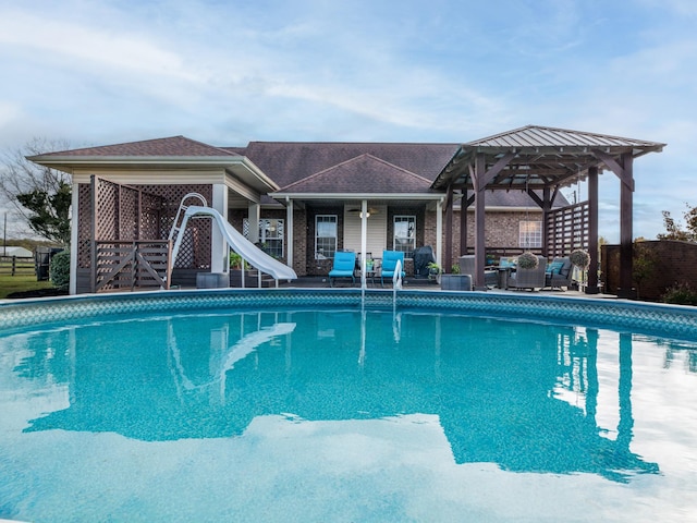 view of pool featuring a water slide, a gazebo, fence, and a patio area