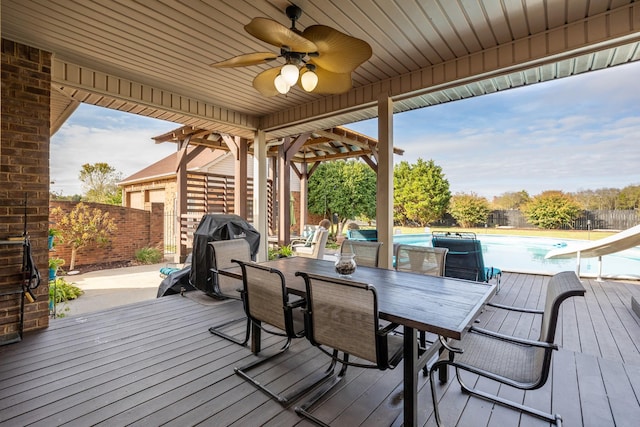 wooden terrace featuring a fenced backyard, a ceiling fan, a grill, and outdoor dining space