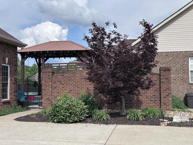 view of home's exterior featuring brick siding, a gazebo, and fence