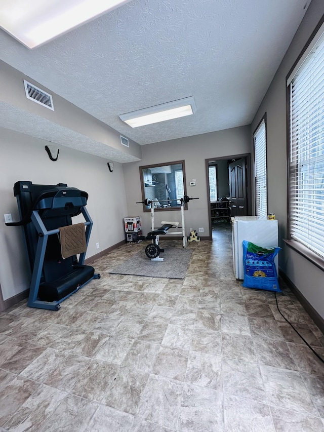 living room with baseboards, stone finish flooring, and a textured ceiling