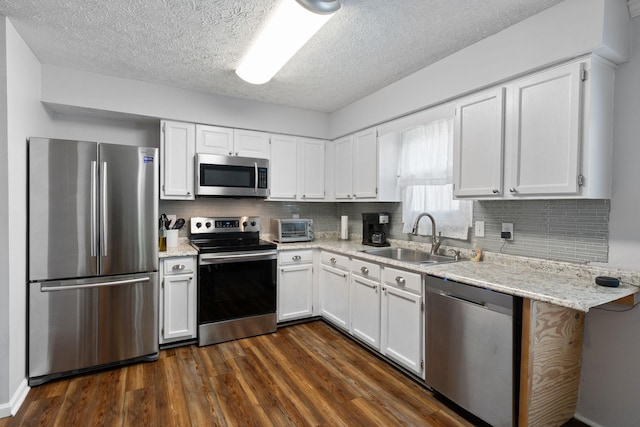 kitchen with stainless steel appliances, a sink, dark wood-style floors, white cabinets, and a textured ceiling