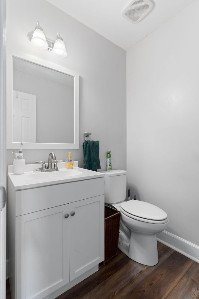 bathroom featuring toilet, wood finished floors, vanity, and baseboards