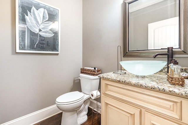 bathroom featuring baseboards, wood finished floors, toilet, and vanity