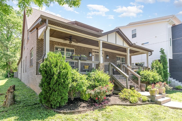 view of front of home with a ceiling fan, stairway, brick siding, and a front yard