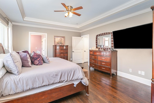 bedroom featuring a tray ceiling, dark wood-style floors, crown molding, baseboards, and a ceiling fan