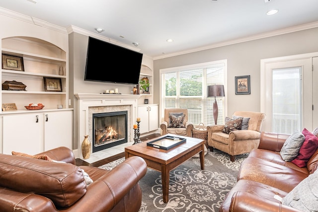 living room featuring crown molding, a fireplace, built in features, recessed lighting, and wood finished floors