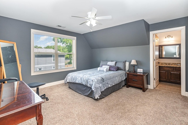 bedroom with light colored carpet, baseboards, vaulted ceiling, ensuite bath, and ceiling fan